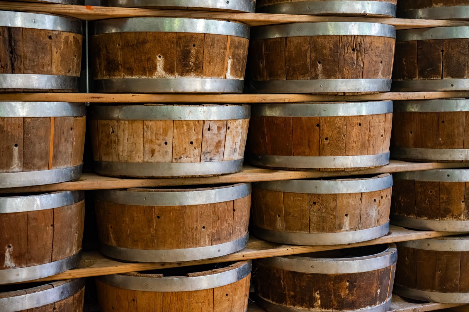 Botticelle di legno impilate su scaffali, in una cantina di invecchiamento