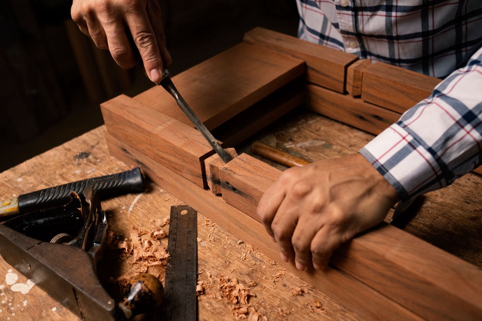 Mani che lavorano il legno con lo scalpello su un banco da falegname